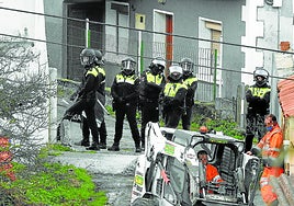 Policías municipales, con cascos y escudos, protegen a unos obreros amenazados por el hijo de la anciana, en noviembre de 2020.