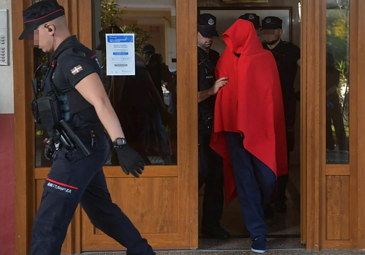 El detenido ha salido de la vivienda acompañado de varios agentes de la Ertzaintza y cubriendo su rostro con una manta roja.