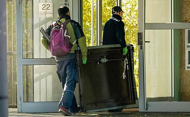 Operarios transportan una puerta antiokupas para instalar en el domicilio recuperado.