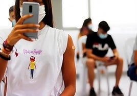 En la imagen una adolescente se hace una foto del brazo con la tirita tras recibir su primera dosis de la vacuna.