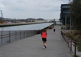 Jóvenes corren por el paseo del Canal, frente a las obras en la isla de Zorrozaurre.