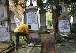 Una persona deposita flores en una sepultura del cementerio de Santa Isabel.