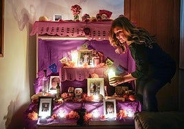 Elena coloca velas y objetos conmemorativos en el altar de muertos.