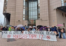 Representantes y miembros de colectivos sociales y sindicales de la localidad bajo la lluvia ayer a las puertas del juzgado de Barakaldo.