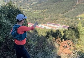 Un montañero observa desde el búnker del Gaztelumendi las naves de la explotación avícola Larrabe.