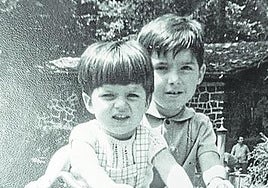 Dos niños, con un triciclo.