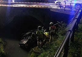 Los bomberos, junto al coche caído al río esta noche en Markina.