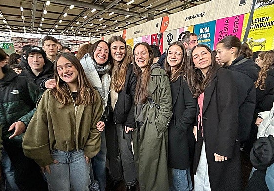 Un grupo de jóvenes alavesas posan junto al logo de la Azoka, en el exterior de Landako Gunea.