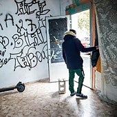 Dos patinetes en una lonja okupada de Coronación. En la puerta, un joven que declara «buscar trabajo» y que en su país era «marinero».