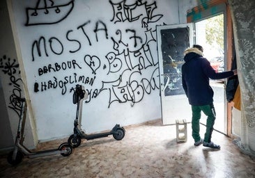 Dos patinetes en una lonja okupada de Coronación. En la puerta, un joven que declara «buscar trabajo» y que en su país era «marinero».
