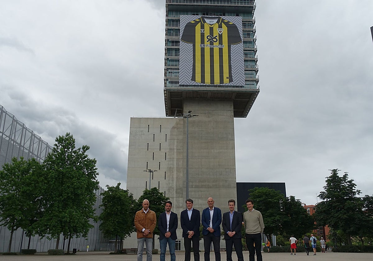 Representantes municipales, del Barakaldo y de Hummel posan frente a la gigante lona de la camiseta que luce en el BEC.