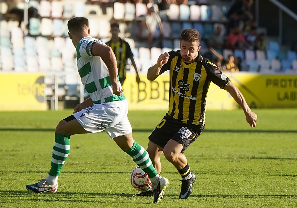 'Okolo' conduce el balón ante la oposición de un jugador del Extremadura.