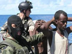 Un soldado de la fragata francesa 'Nivose' detiene a uno de los once piratas capturados en Somalia./ Reuters