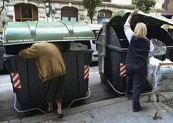 Dos personas busan en cubos de basura. / Reuters
