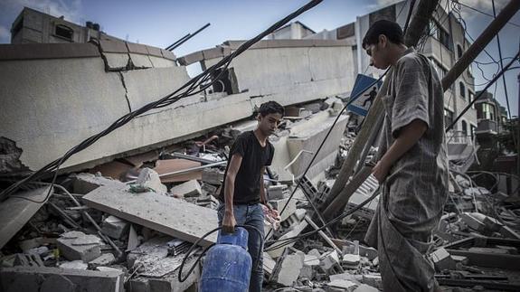 Varios palestinos recogen los utensilios que todavían son útiles entre los escombros. / Efe