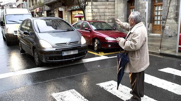 Una persona mayor solicita a un conductor que detenga su vehículo frente a un paso de peatones.