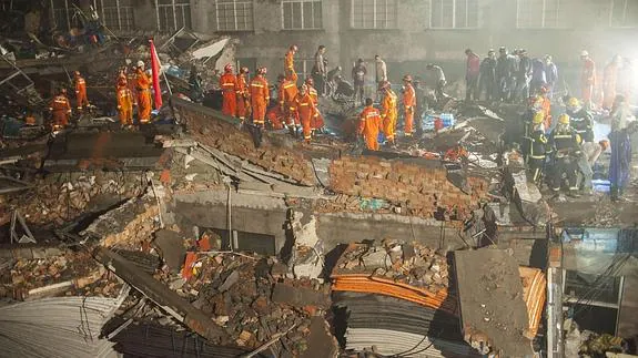 Los miembros del equipo de rescate inspeccionan los restos de la fábrica derrumbada en China.