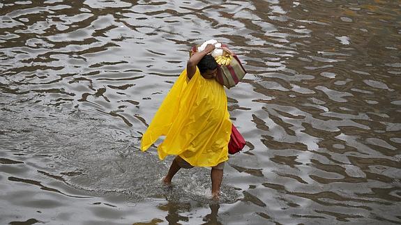 Un hombre traslada algunas de sus pertenencias en una calle inundada de Calcuta.