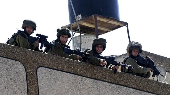 Varios soldados israelíes vigilan a un grupo de manifestantes palestinos en Cisjordania.