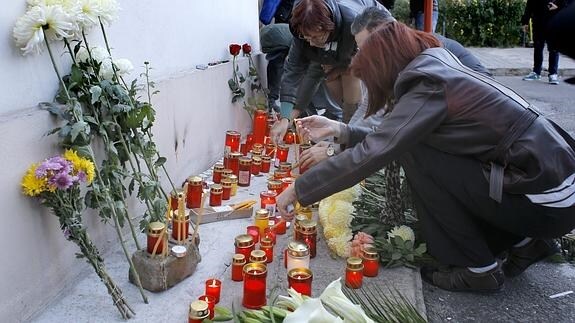 Varias personas ponen velas en el lugar de la tragedia.