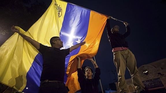 Un grupo de personas celebra la victoria obtenida por la coalición opositora Mesa de Unidad Democrática (MUD).