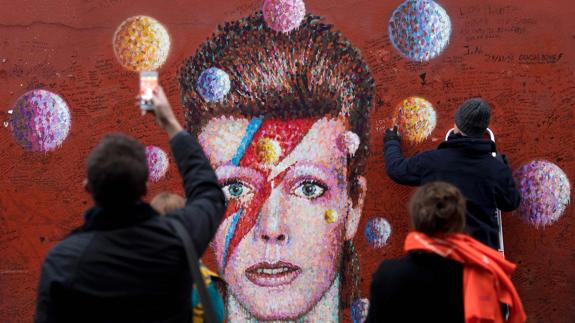 Varias personas ante un retrato de David Bowie en el barrio londinense de Brixton.