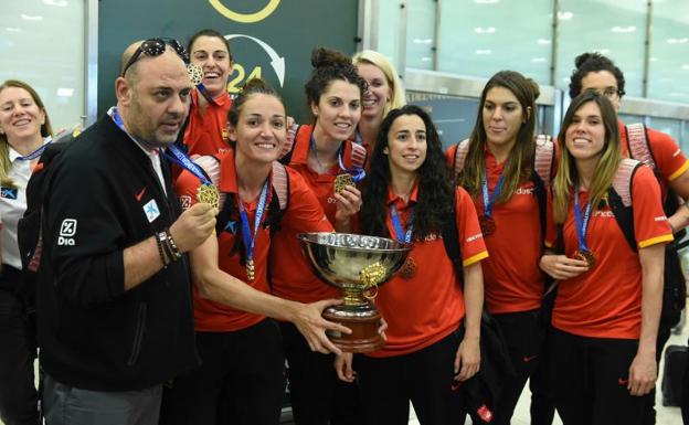 Lucas Mondelo (i), con las jugadoras españolas, con la copa de campeonas en el aeropuerto de Barajas. 