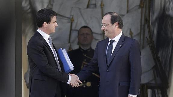 Manuel Valls estrecha la mano a Francois Hollande.