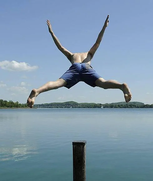 Un joven salta al agua en un lago.