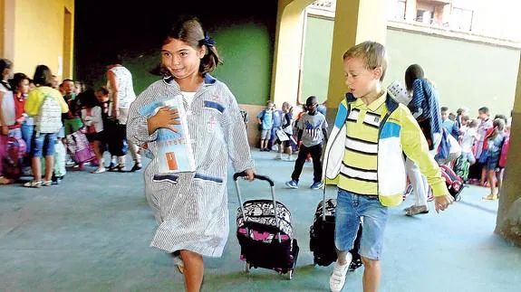 Dos niños arrastran sus mochilas, camino del aula en la que comenzarán el nuevo curso escolar. 
