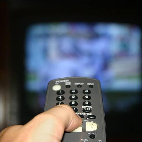 Un hombre cambia de canal con el mando.