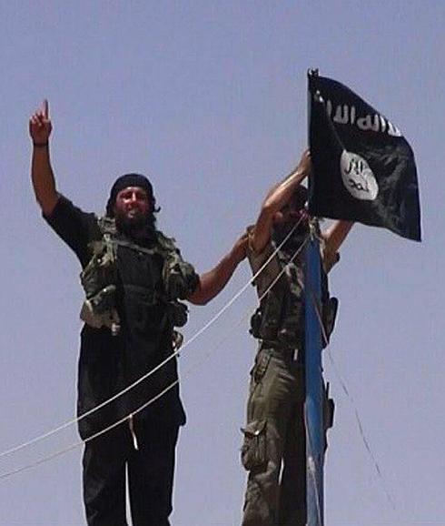 Miembros del Estado Islámico colocan una bandera de su grupo en un antiguo fuerte militar. 