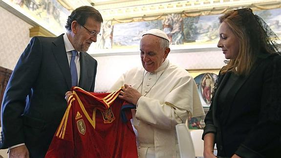 Rajoy, acompañado por su mujer, entrega una camiseta de ‘La Roja’ al Papa. 