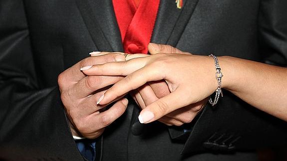 Un marido coloca el anillo de recien casados en la boda.