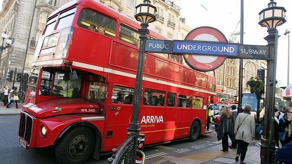 Un autobús circula en el centro de Londres junto a una estación de metro.