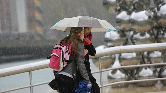 Dos turistas se protegen de la lluvia en Bilbao. 