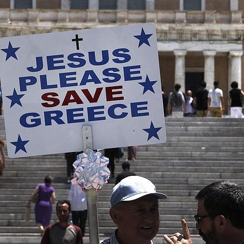 Un hombre sostiene una pancarta en la que se lee: "Jesús, por favor salva a Grecia ", en la plaza Syntagma de Atenas, Grecia.