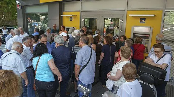 Numerosos griegos hacen cola a las puertas de un banco.