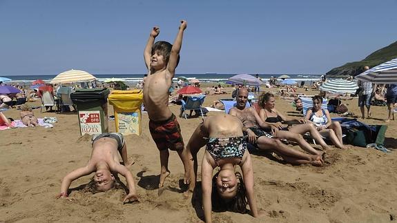 Tres niños se divierten en la playa de La Arena.