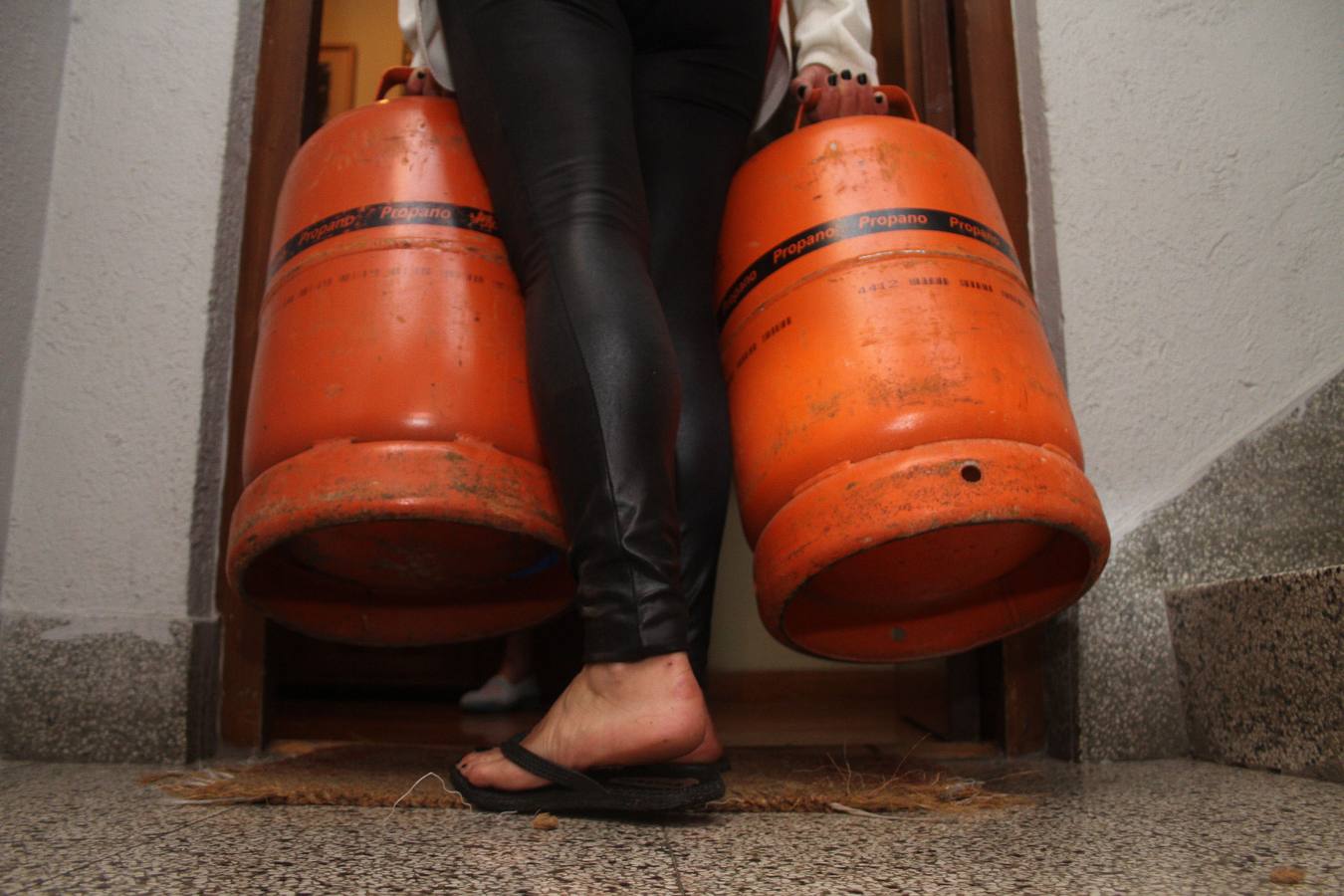 Una mujer carga con dos bombonas de butano en Llodio. 