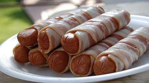 Imagen de unas salchichas cubiertas por una loncha de bacon.