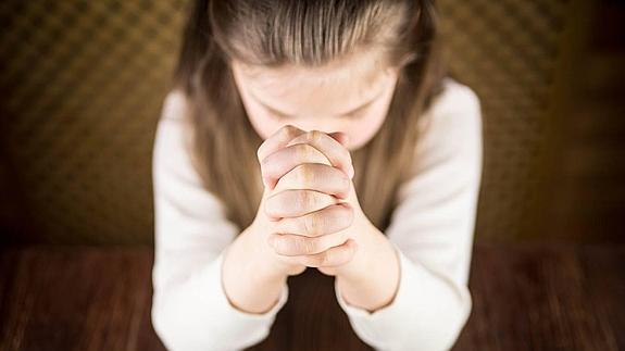 Una niña rezando.