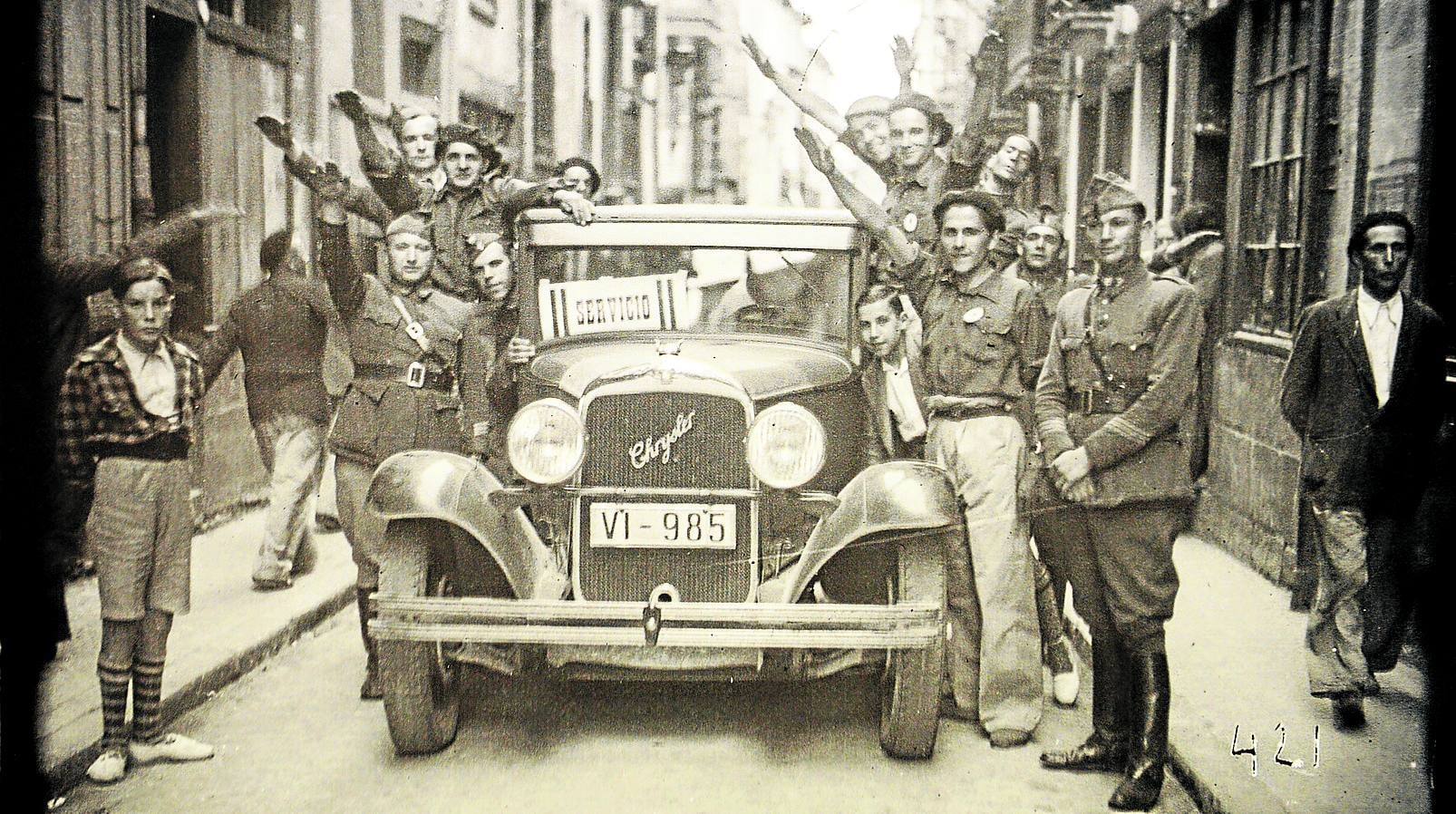 Una camioneta llena de soldados y requetés hacen el saludo fascista en una calle de Vitoria.