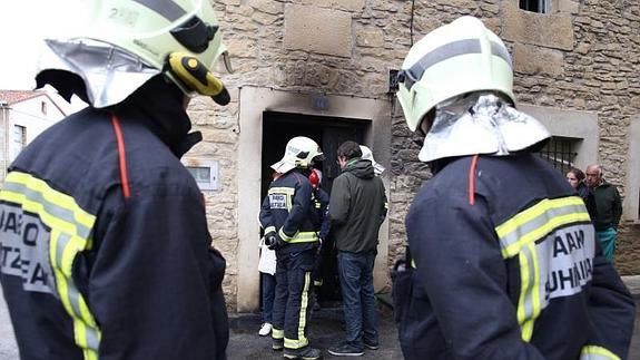 Bomberos inspeccionan, ya por la mañana, la vivienda que ardió de madrugada en Tuesta. 