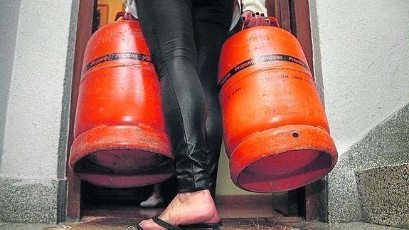 Un ama de casa introduce dos bombonas de propano en su hogar.