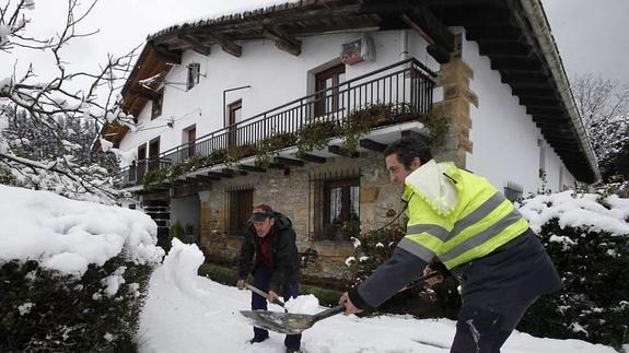 Un par de hombres retiran nieve en un baserri de Muxika.
