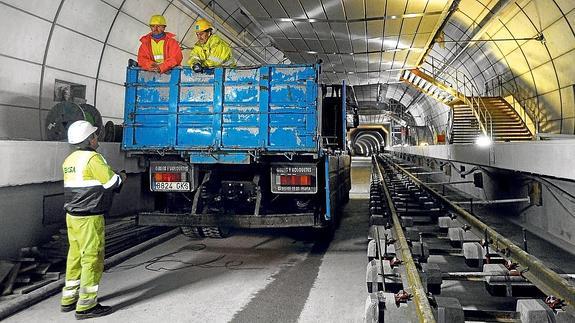 Tres trabajadores aguardan su turno para proceder a la instalación del primer tramo de vía de la Línea 3, en la estación de Otxarkoaga.