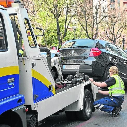 Un operario engancha un coche mal aparcado a la grúa.