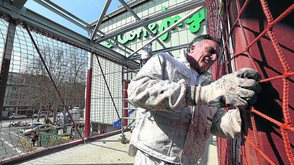 Un trabajador realiza trabajos de pintura en la pasarela de El Corte Inglés, en la mañana de ayer. 