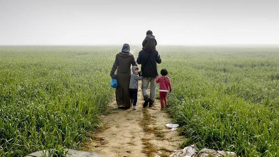 Una familia de refugiados camina por un sendero cercano al campo de Idomeni, en la frontera de Macedonia.